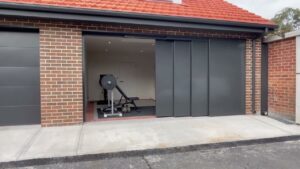 Modern home with a wide sliding garage door opening to a clean, organized garage gym