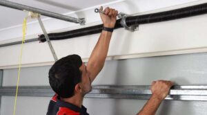 A professional technician using a wrench to repair a torsion spring on a residential garage door system.
